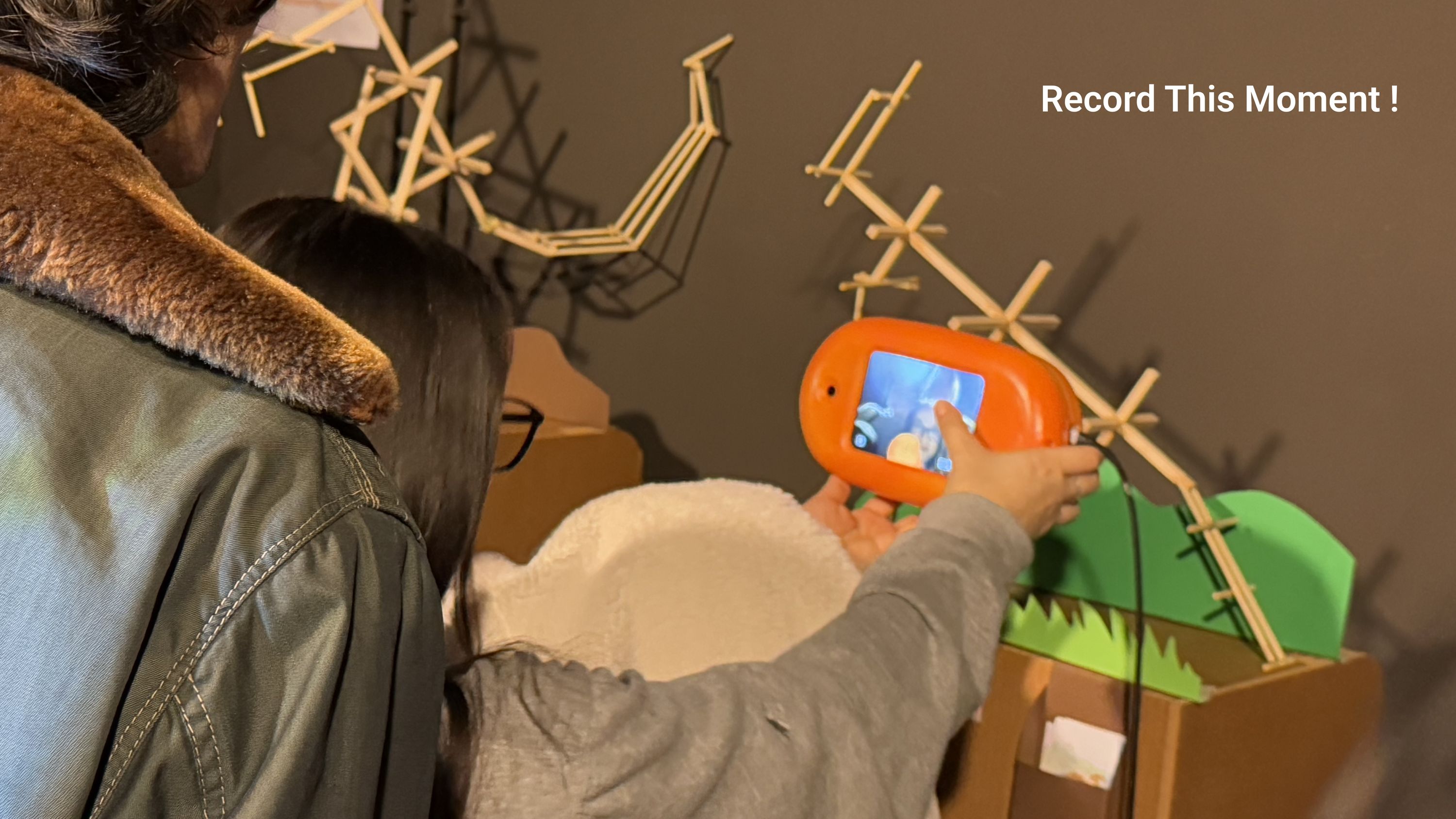 A visitor holding Ecco up to photograph the exhibit, captioned record this moment